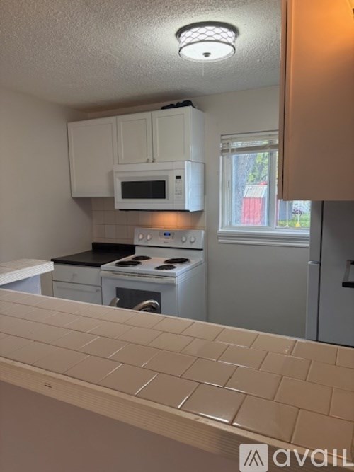 A kitchen with white cabinets and a white microwave above the stove.