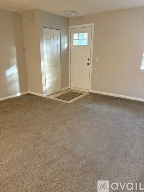 A room with a carpeted floor and two doors.