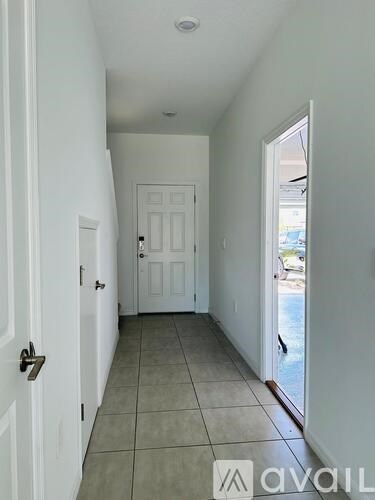 A hallway with a white door and tiled floor.