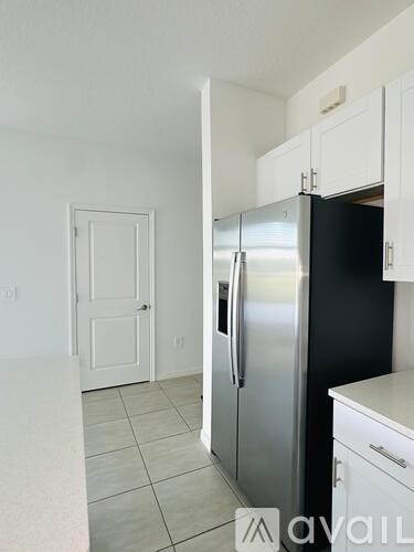 A kitchen with a stainless steel refrigerator and white cabinets.