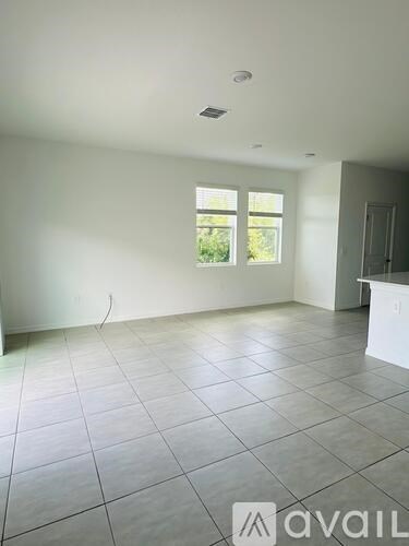 A room with white walls and tile flooring, with a window and a door visible.