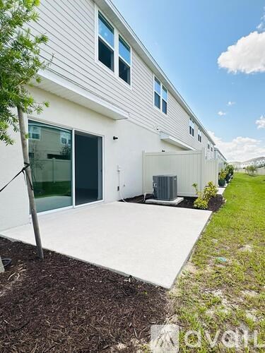 A white house with a large driveway and a tree in front.