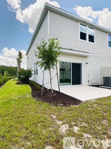 A white house with a tree in front of it.