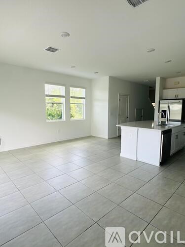 A spacious kitchen and living room with white cabinets and a large window.