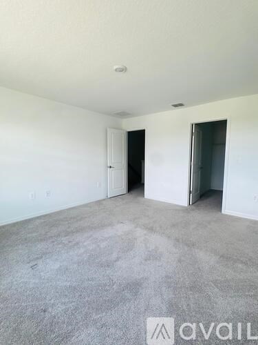 A room with a carpeted floor and two doors.