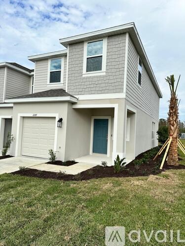 A modern house with a grey and white exterior and a palm tree in front.