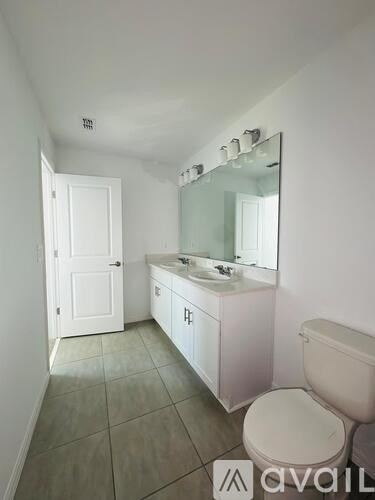 A bathroom with a toilet, sink, and mirror.