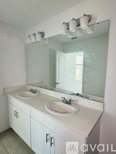A bathroom with a white vanity and a large mirror.