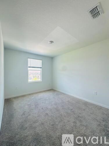A room with a window and a carpeted floor.