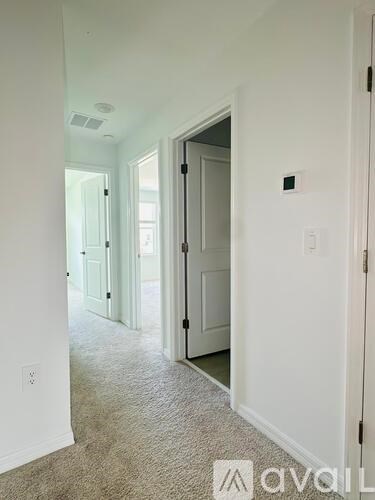 A hallway with a carpeted floor and white walls.