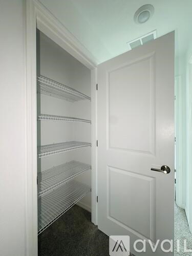 A white door with a handle is open to a room with a white wall and a white ceiling.