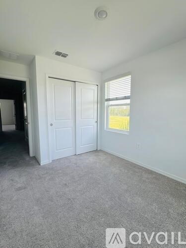 A room with a carpeted floor, a white door, and a window with blinds.