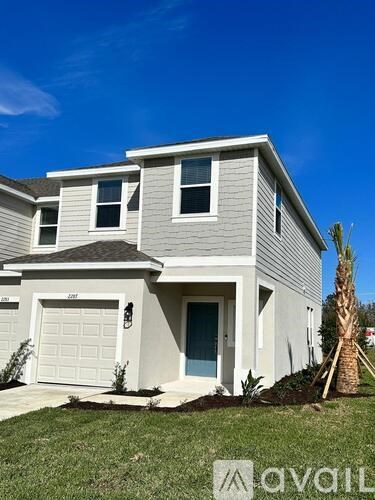 A two-story house with a garage and a palm tree in front.