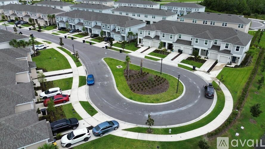 A bird's eye view of a roundabout with cars and houses around it.