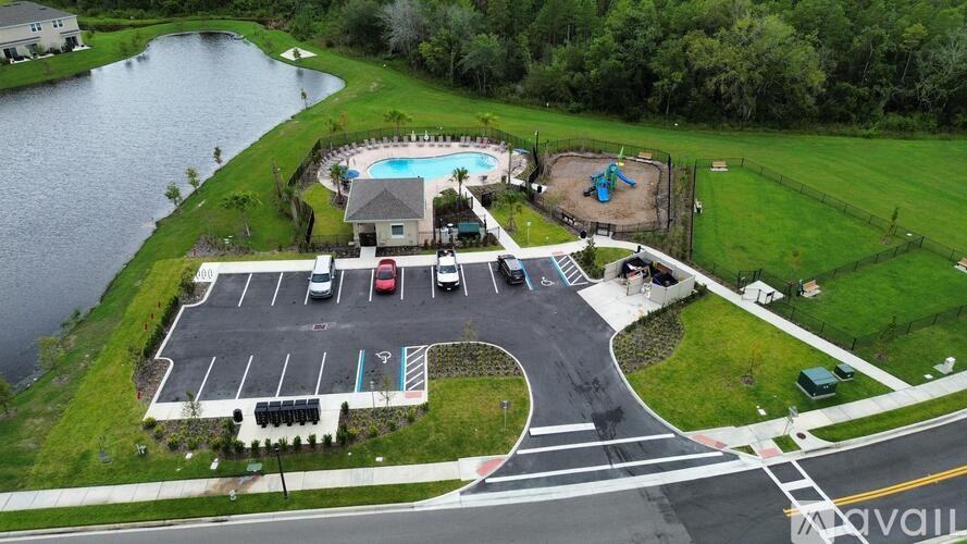 A large building with a pool and a playground is surrounded by a parking lot.
