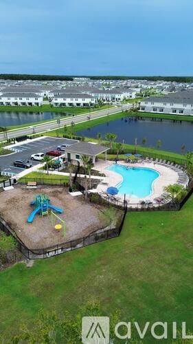 A playground with a blue slide and a pool is surrounded by a fence.