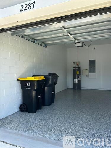Three black and yellow trash cans are placed under a white wall with a number 2287 on it.