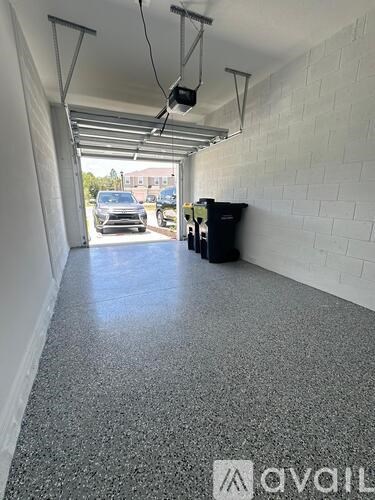 A long white hallway with a black trash can and a white wall.