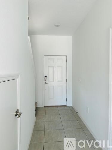 A hallway with a white door and tiled floor.