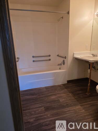 A bathroom with a white tub and a wooden floor.
