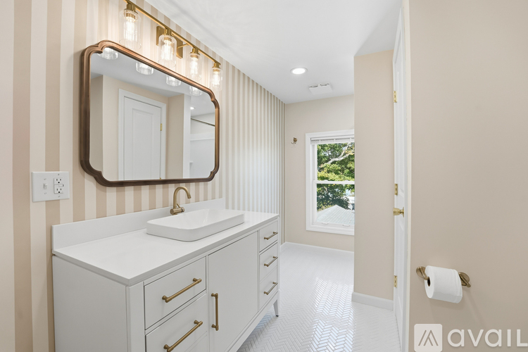 A bathroom with a sink, mirror, and striped wallpaper.