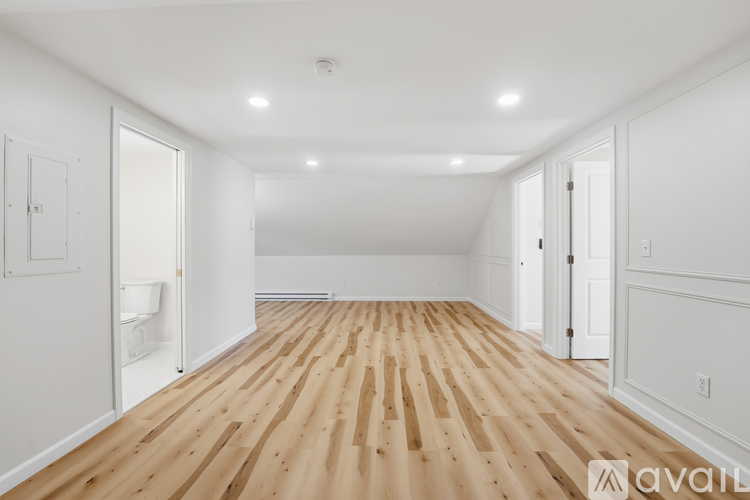 A spacious room with wooden flooring and white walls.