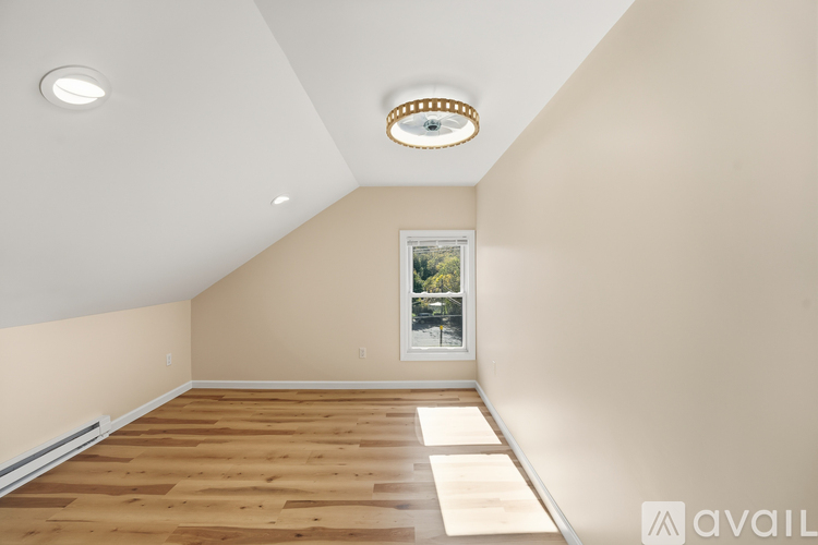 A room with wooden flooring and a window showing trees outside.