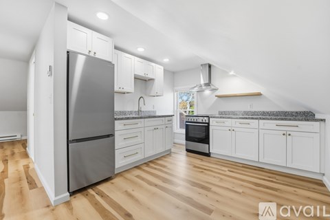 A kitchen with white cabinets and a stainless steel refrigerator.