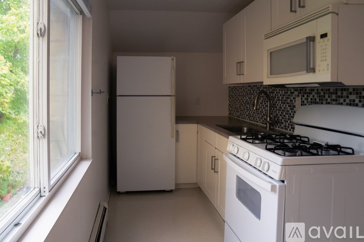 A kitchen with a white refrigerator, white oven, and a black and white tiled backsplash.