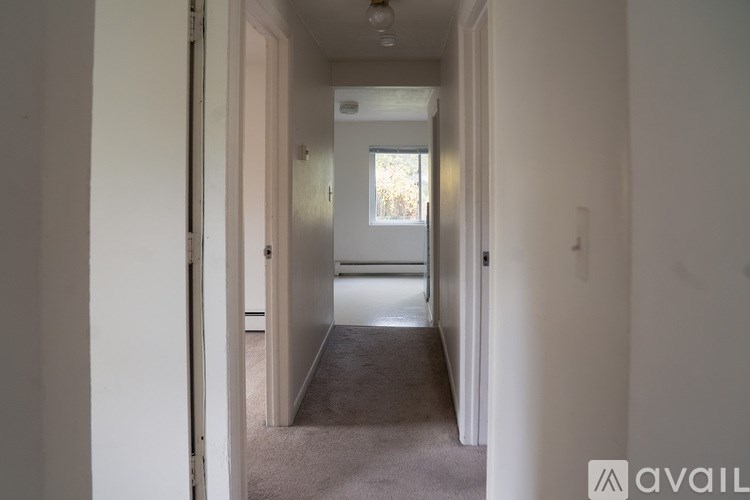 A hallway with a carpeted floor and white walls.