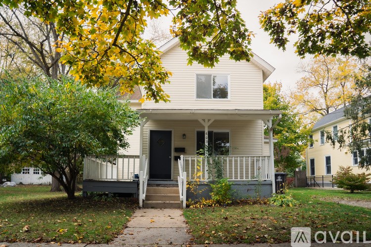 A house with a front porch and a tree with yellow leaves.