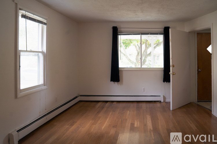 A room with wooden floors and a window with black curtains.