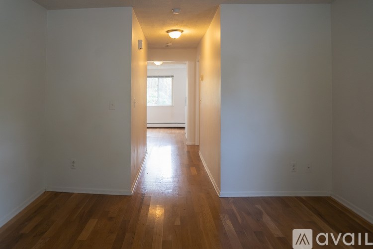 A long hallway with wood floors and white walls.