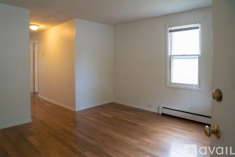 A room with wooden floors and a window with a white frame.