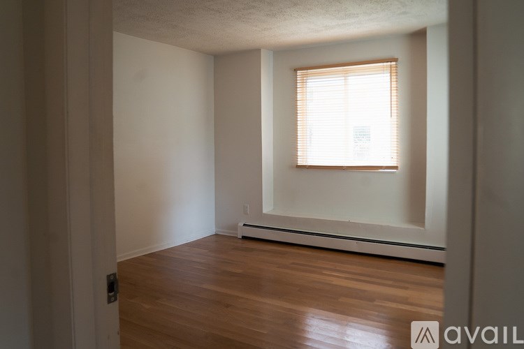 A room with wooden floors and a window with blinds.