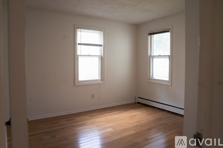 A room with wooden floors and two windows.