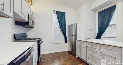 A kitchen with a stainless steel refrigerator and wooden floors.