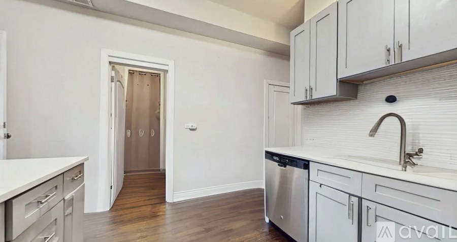 A kitchen with white cabinets and a wooden floor.
