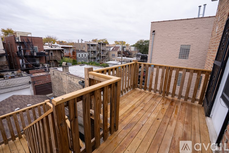 A wooden deck with a railing and a view of a cityscape.
