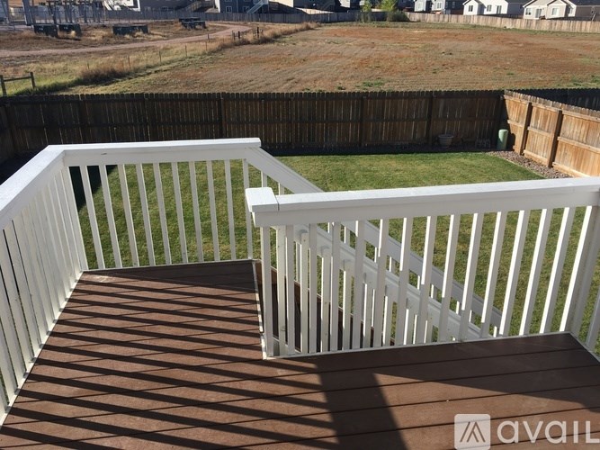 A deck with white railings and a brown floor.
