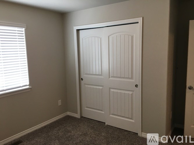 A white door with a window to the left is in a room with carpeted flooring.