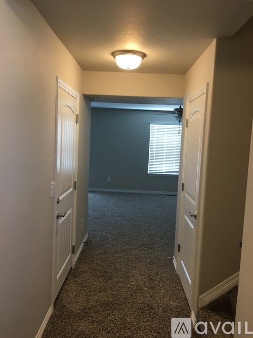 A hallway with carpeted flooring and white walls.