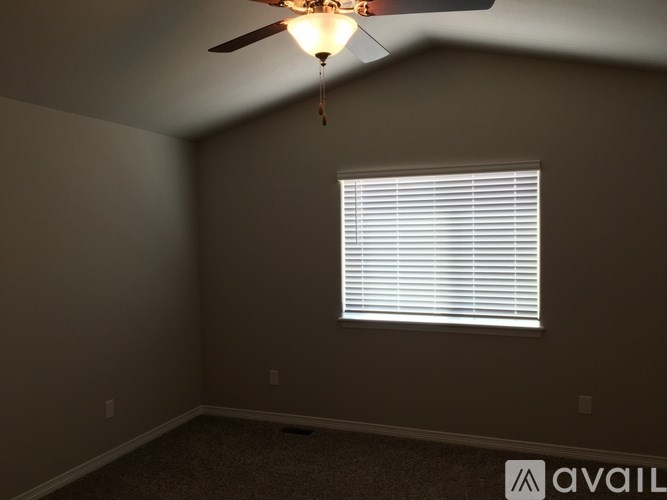 A room with a ceiling fan and a window with blinds.