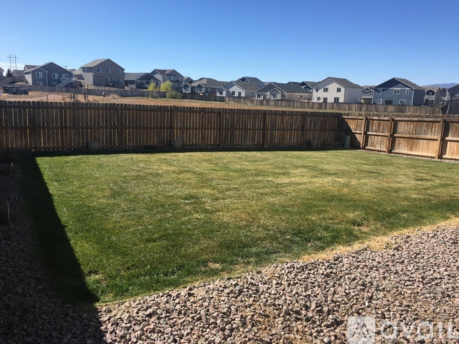A backyard with a gravel area and a wooden fence.
