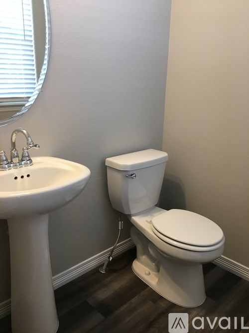 A white toilet sits next to a white pedestal sink in a bathroom.