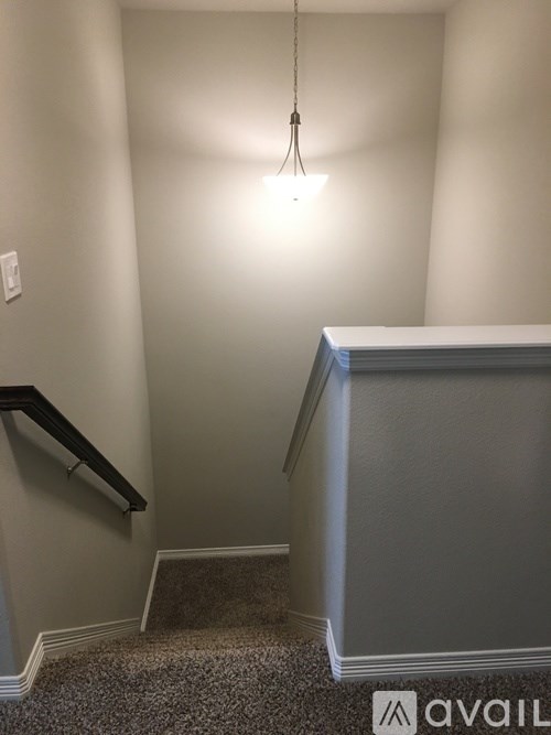 A staircase with a carpeted runner and a light hanging from the ceiling.