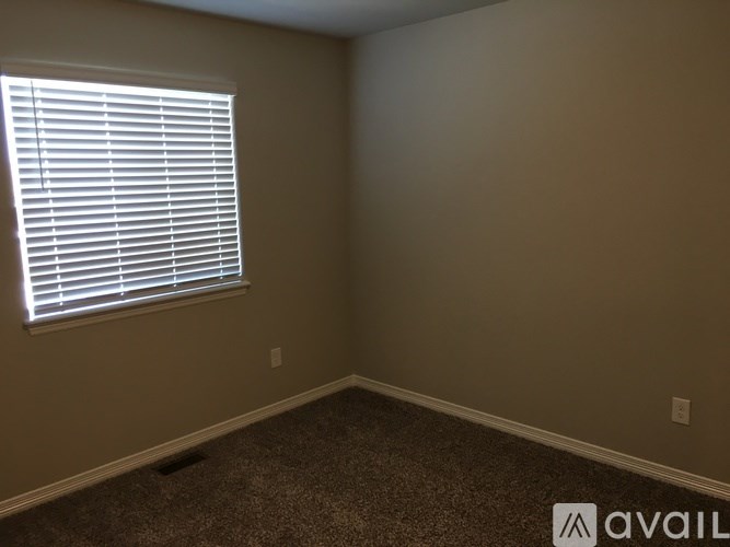 A room with a window covered by white blinds.