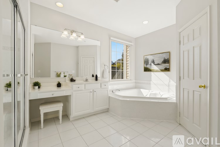 A white bathroom with a tub, sink, and mirror.