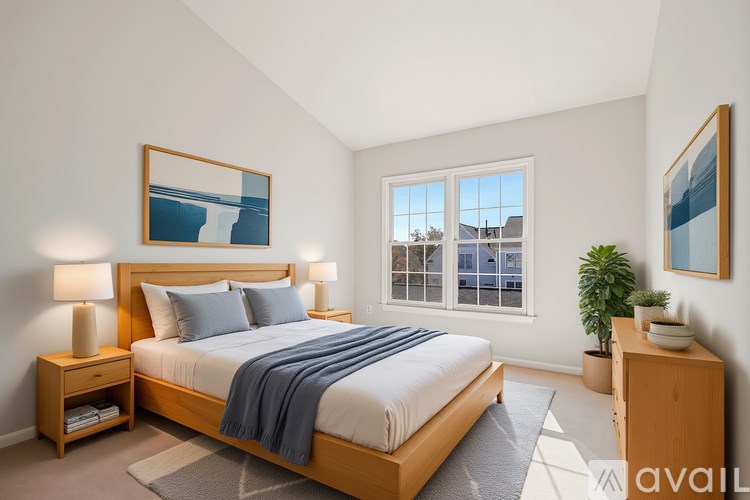 A bedroom with a large bed and a window overlooking a house.
