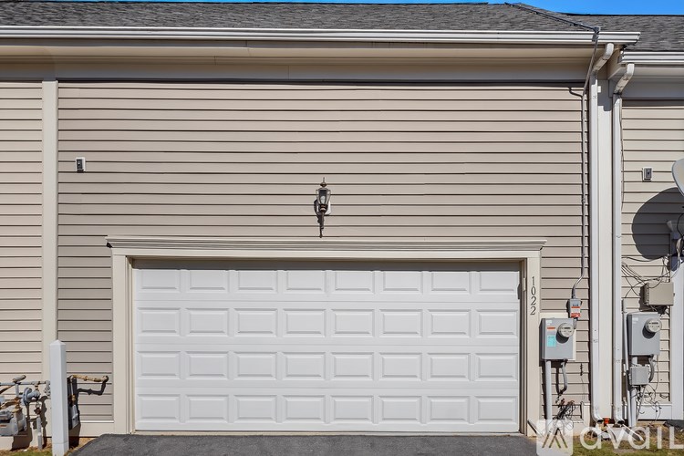 A white garage door is closed and there is a black mat on the ground.